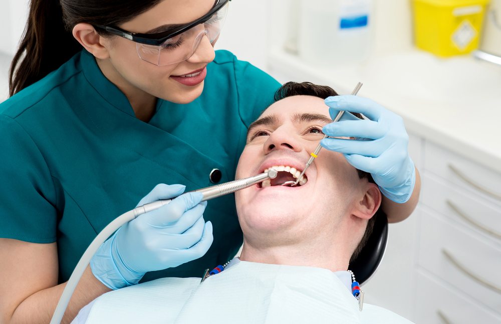 A female dental hygienist cleans a young man's teeth