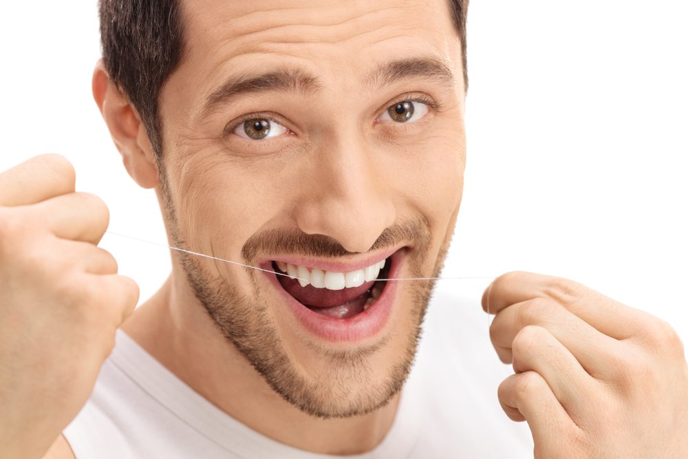 Young man flossing his teeth