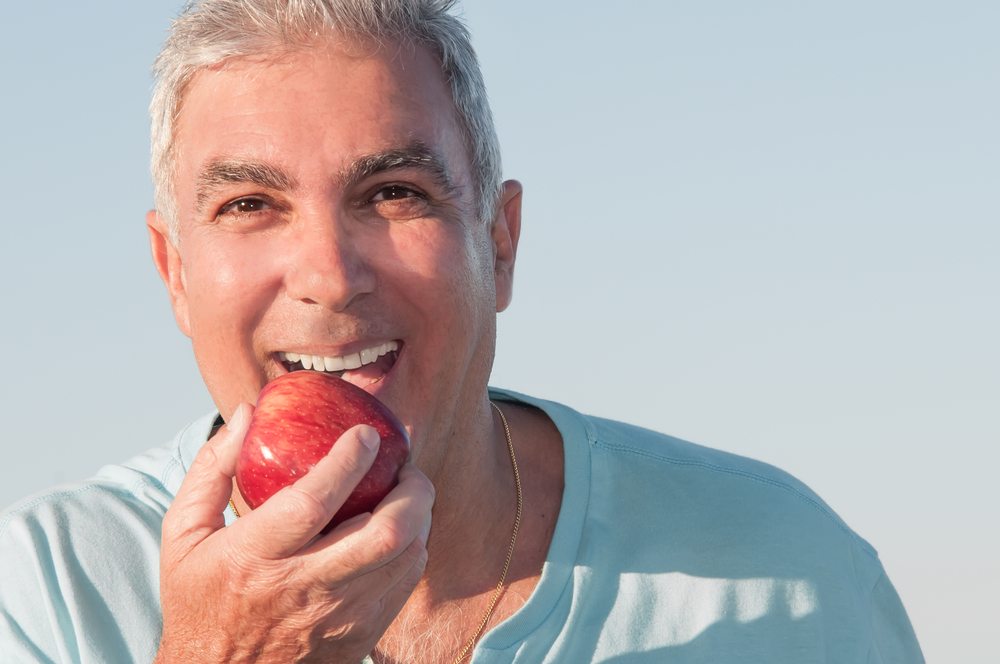 Man with dental implants bites into an apple